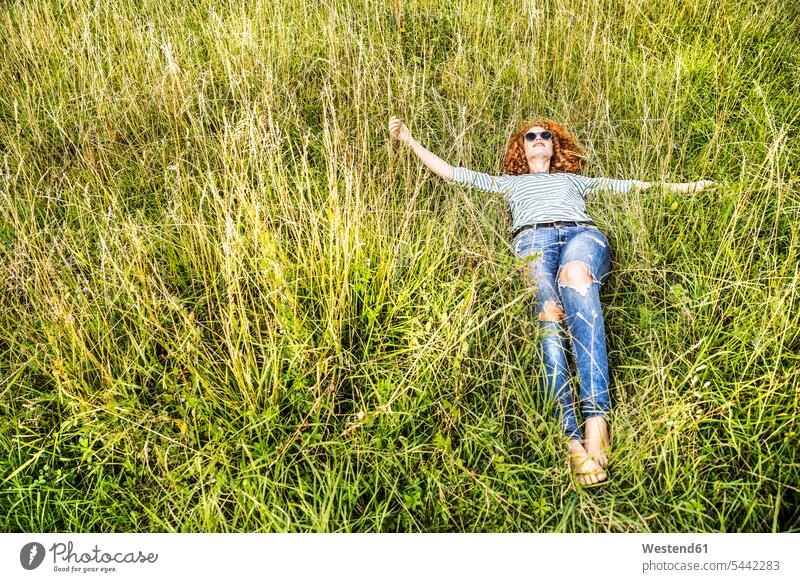 Young woman relaxing on a meadow lying laying down lie lying down meadows females women Adults grown-ups grownups adult people persons human being humans