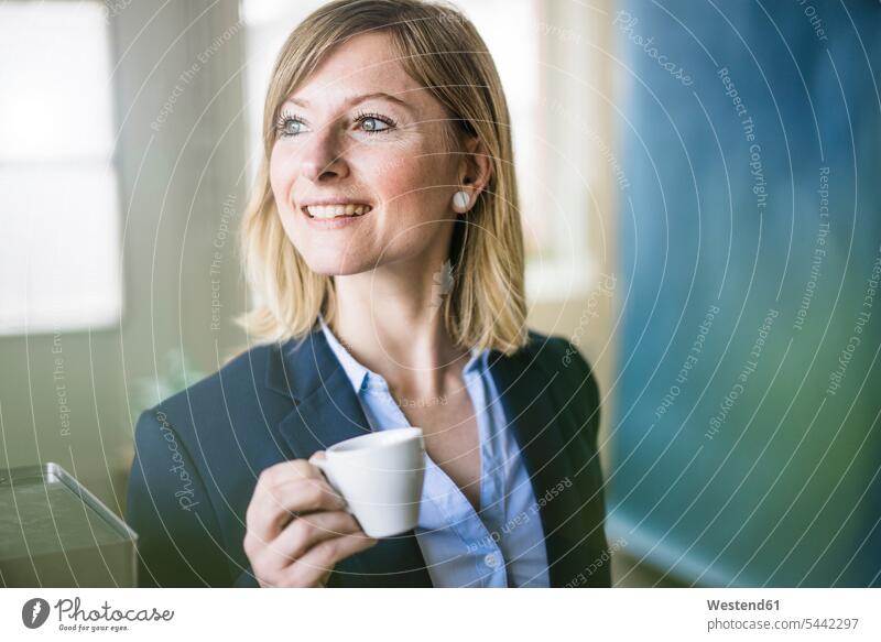 Smiling businesswoman holding espresso cup in office smiling smile businesswomen business woman business women offices office room office rooms Coffee