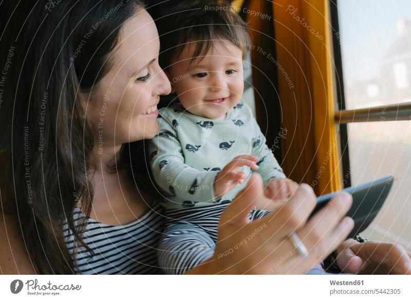 Happy mother and baby girl using smartphone while traveling by train mobile phone mobiles mobile phones Cellphone cell phone cell phones travelling infants