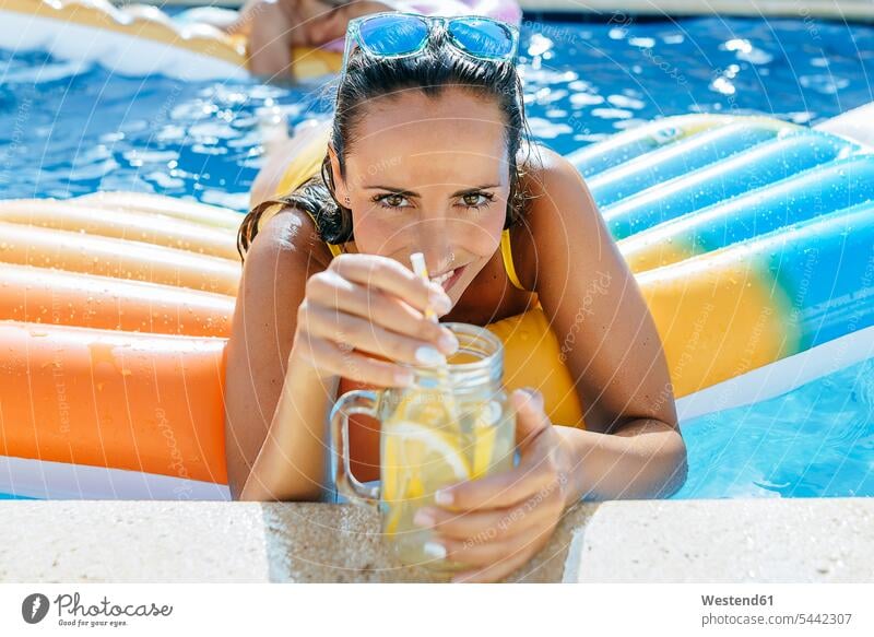 Young woman in swimming pool with drink at the poolside relaxed relaxation females women swimming pools relaxing Adults grown-ups grownups adult people persons