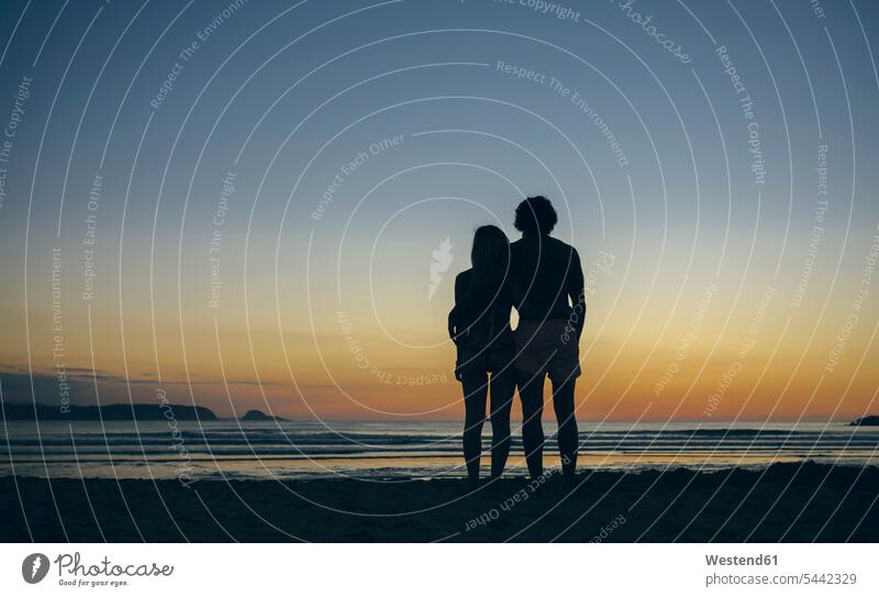 Young couple watching the sunset on the beach twosomes partnership couples beaches people persons human being humans human beings vacation Holidays sunsets
