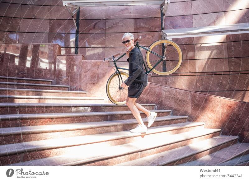 Mature man carrying his bicycle on his shoulders bikes bicycles ascending stairs riding bicycle riding bike bike riding cycling bicycling pedaling men males