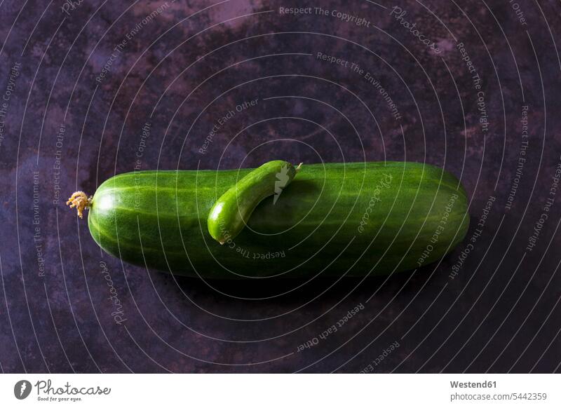Two organic cucumbers on dark ground green on top of gleaming two objects 2 sliced organic edibles firm size comparison dark background Size Difference
