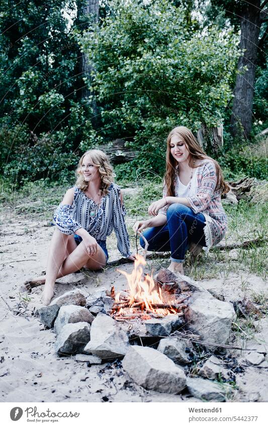 Two teenage girls sitting at campfire Camp Fire Campfire Bonfire female friends beach beaches mate friendship smiling smile Teenage Girls female teenagers