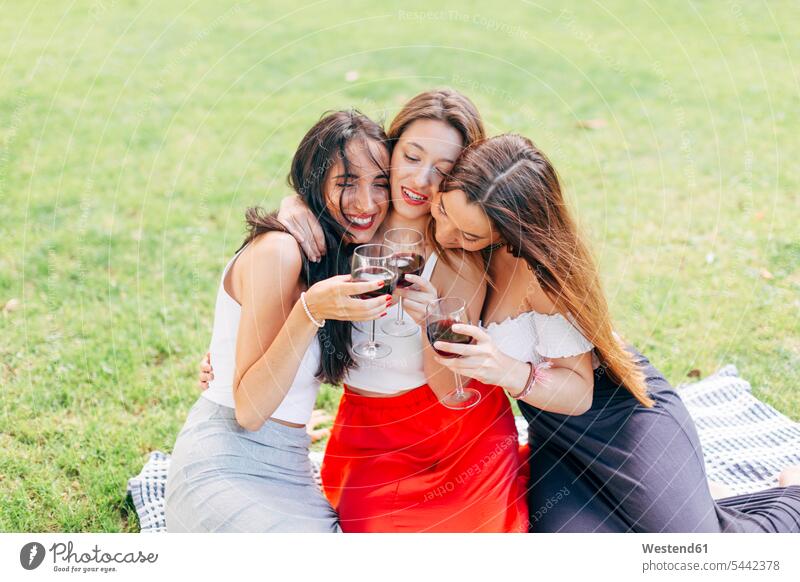 Happy friends in a park hugging and enjoying red wine Red Wine Red Wines drinking parks embracing embrace Embracement female friends Alcohol alcoholic beverage