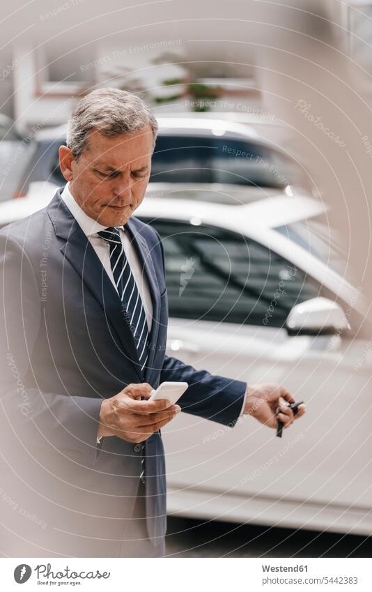 Businessman checking message while using remote control key of car Smartphone iPhone Smartphones mobile phone mobiles mobile phones Cellphone cell phone