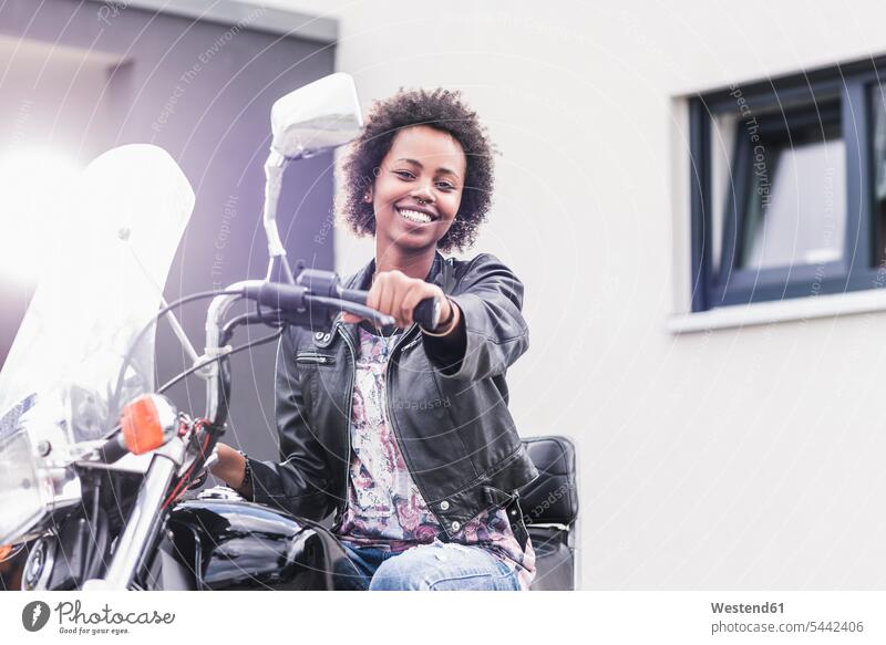 Portrait of smiling young woman with her motorcycle motorbike Motor Cycle females women smile motor vehicle road vehicle road vehicles motor vehicles Adults