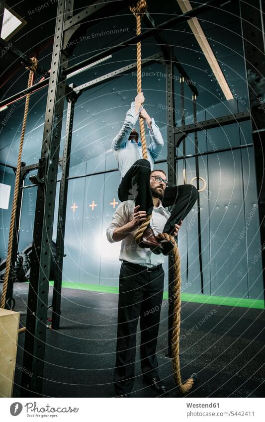 Businessman supporting colleague, climbing a rope gym gyms Health Club manager managers Business man Businessmen Business men promotion ropes Support fitness