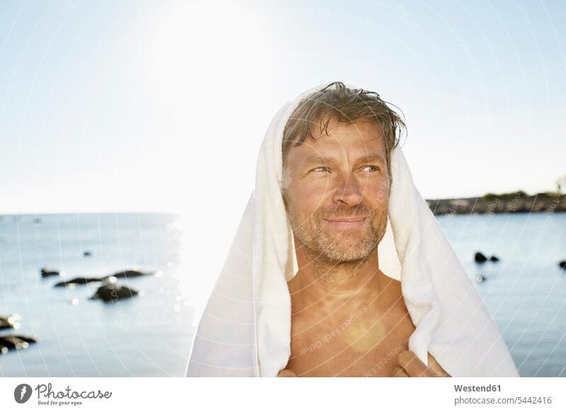 Portrait of smiling man with towel in front of the sea portrait portraits men males Adults grown-ups grownups adult people persons human being humans