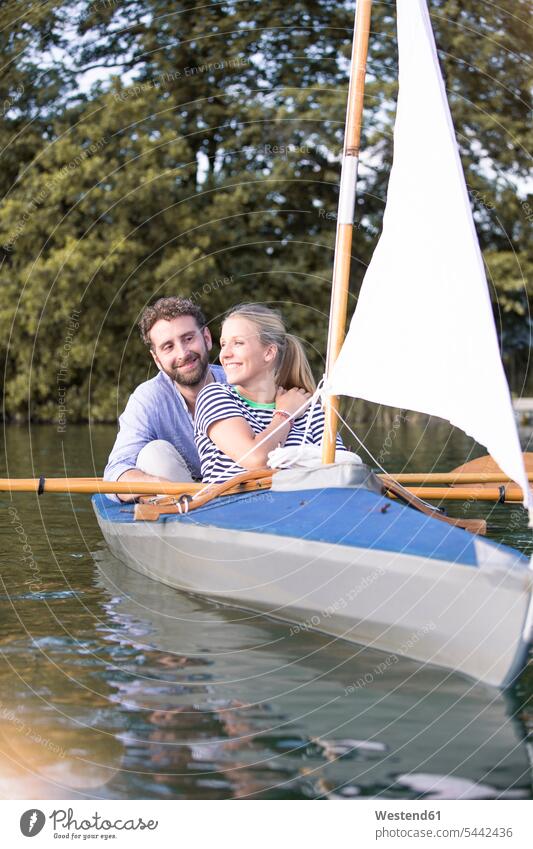 Happy young couple enjoying a trip in a canoe with sail excursion Getaway Trip Tours Trips twosomes partnership couples happiness happy indulgence enjoyment