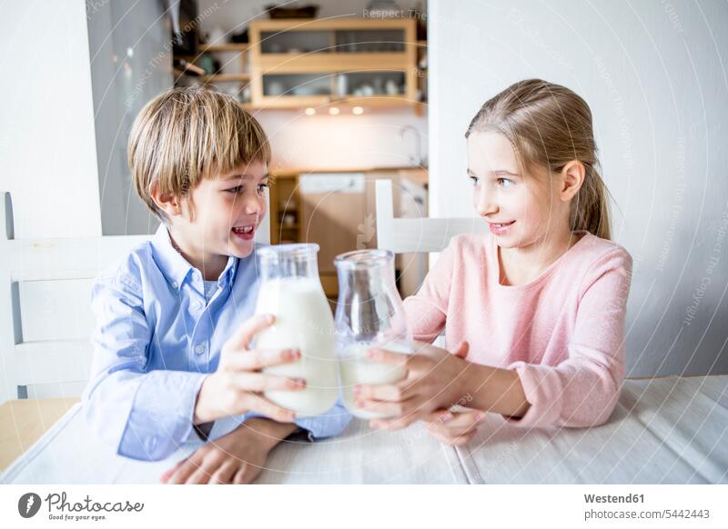 Brother and sister clinking milk glasses Milk sisters brother brothers smiling smile drinking Drink beverages Drinks Beverage food and drink Nutrition