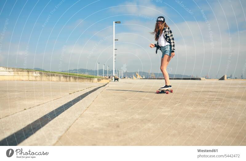 Young woman longboarding on beach promenade females women female skateboarder female skater female skateboarders skateboarding Adults grown-ups grownups adult