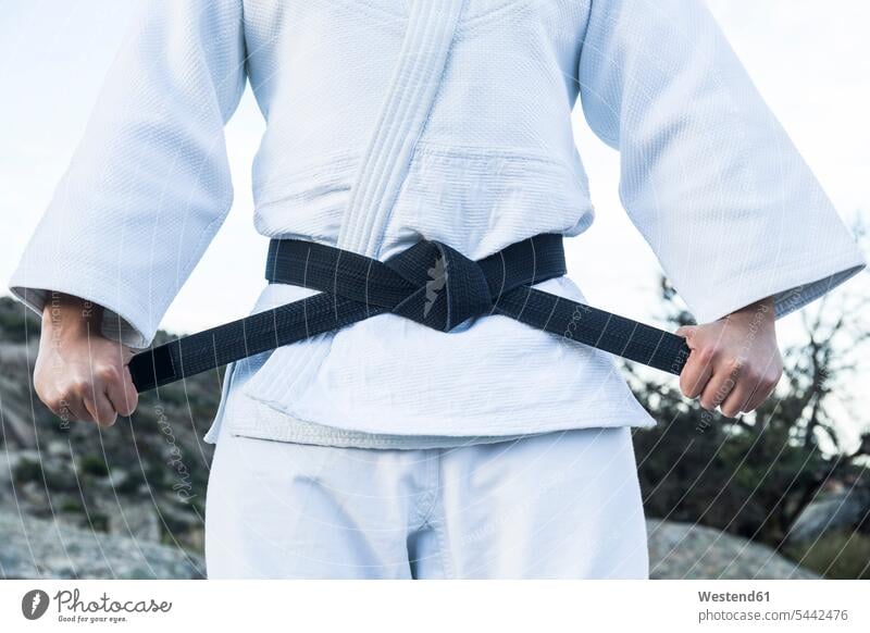 Man tying his black belt during a martial arts training combative sport belts exercising exercise practising man men males sports Adults grown-ups grownups