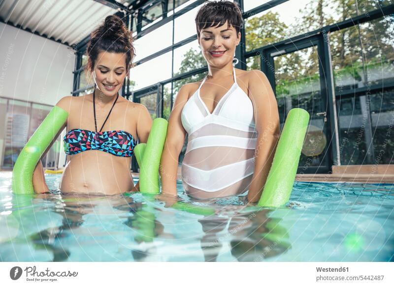 Two pregnant women doing water gymnastics in indoor swimming pool indoor swimming pools Pregnant Woman aqua aerobics woman females swimming bath