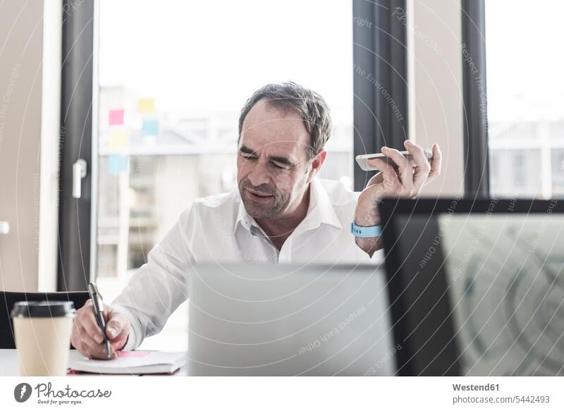 Businessman working at desk in office signing signature Business man Businessmen Business men document paper documents papers contract contracts At Work