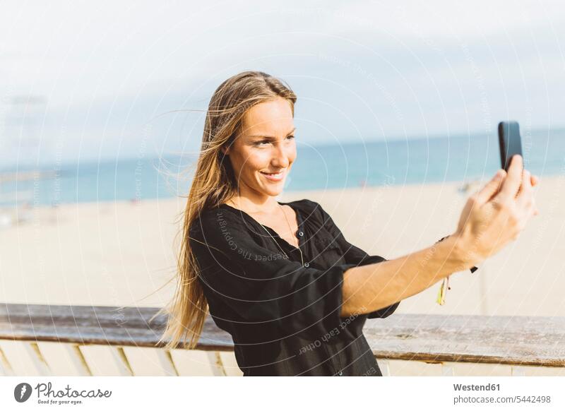 Smiling young woman taking a selfie at the beach Selfie Selfies smiling smile females women happiness happy Adults grown-ups grownups adult people persons