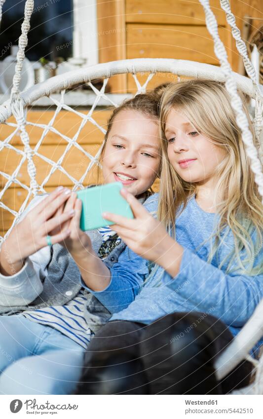 Portrait of two girls relaxing in a hanging chair taking selfie with smartphone Smartphone iPhone Smartphones Selfie Selfies portrait portraits relaxation