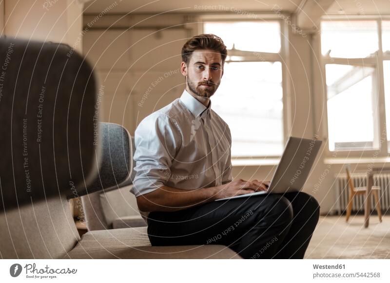 Portrait of young businessman using laptop in a loft Laptop Computers laptops notebook Businessman Business man Businessmen Business men computer computers