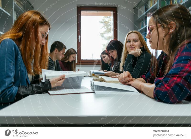 Group of students learning together in a library female students book books higher education building buildings built structure built structures community