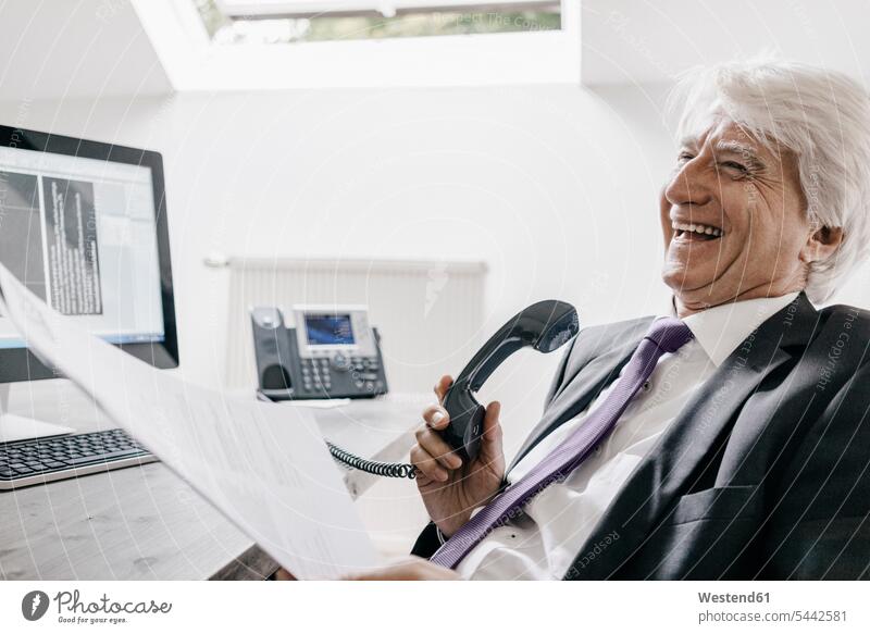 Laughing senior businessman on the phone in his office telephone receiver receivers telephone receivers handset offices office room office rooms Businessman