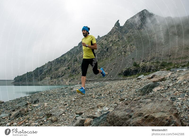 Italy, Alagna, trail runner on the move at a lake near Monte Rosa mountain massif running athlete Sportspeople Sportsman Sportsperson athletes Sportsmen
