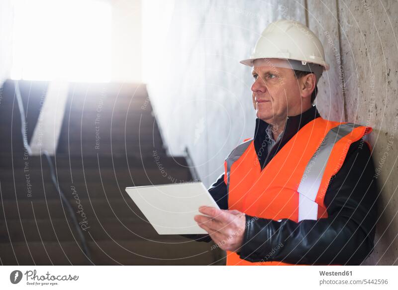 Man with tablet wearing safety vest in building under construction construction site Building Site sites Building Sites construction sites digitizer