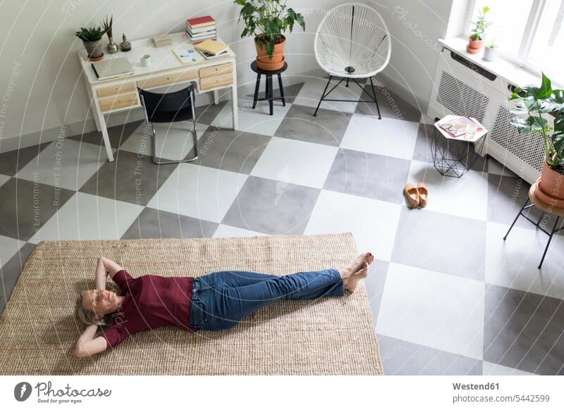 Relaxed mature woman lying on the floor at home females women floors laying down lie lying down relaxed relaxation Adults grown-ups grownups adult people