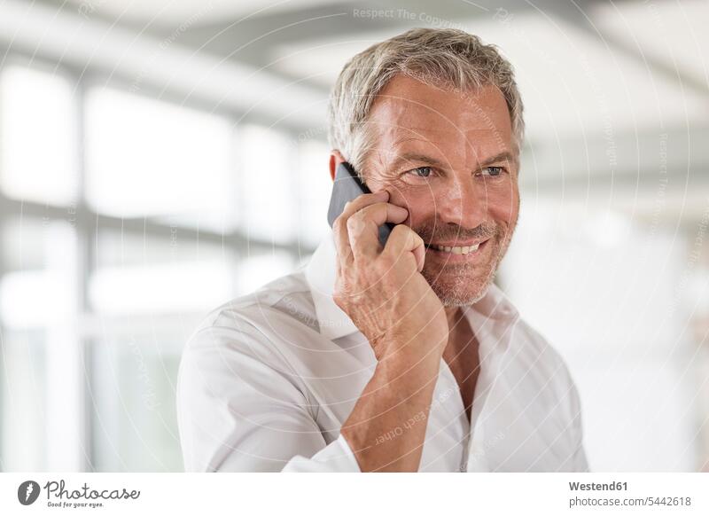 Smiling businessman on cell phone in office Businessman Business man Businessmen Business men smiling smile on the phone call telephoning On The Telephone