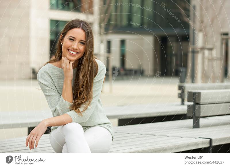 Young woman sitting on a bench, smiling females women Seated benches Adults grown-ups grownups adult people persons human being humans human beings urban