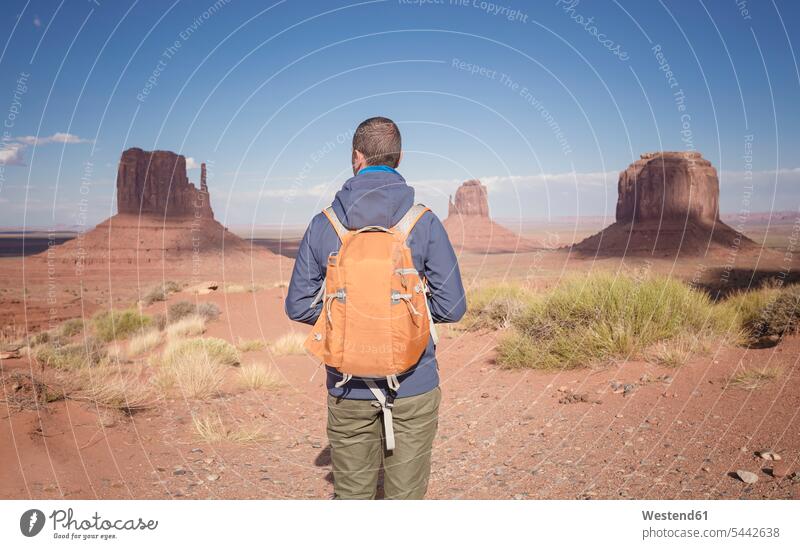 USA, Utah, back view of man with backpack looking at Monument Valley males tourist tourists Adults grown-ups grownups adult people persons human being humans