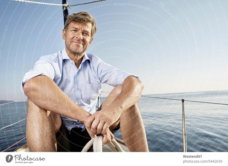 Portrait of smiling mature man sitting on his sailing boat men males portrait portraits Adults grown-ups grownups adult people persons human being humans