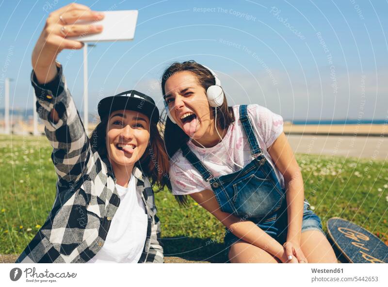 Portrait of two young women taking selfie with smartphone Selfie Selfies portrait portraits female friends mate friendship cheeky impertinent Cheekiness