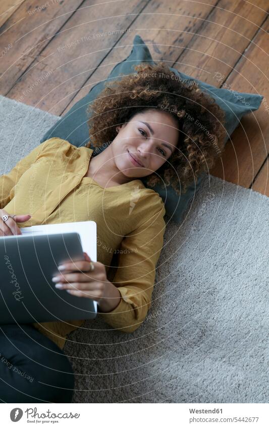 Smiling young woman lying on the floor at home with laptop Laptop Computers laptops notebook floors females women laying down lie lying down smiling smile