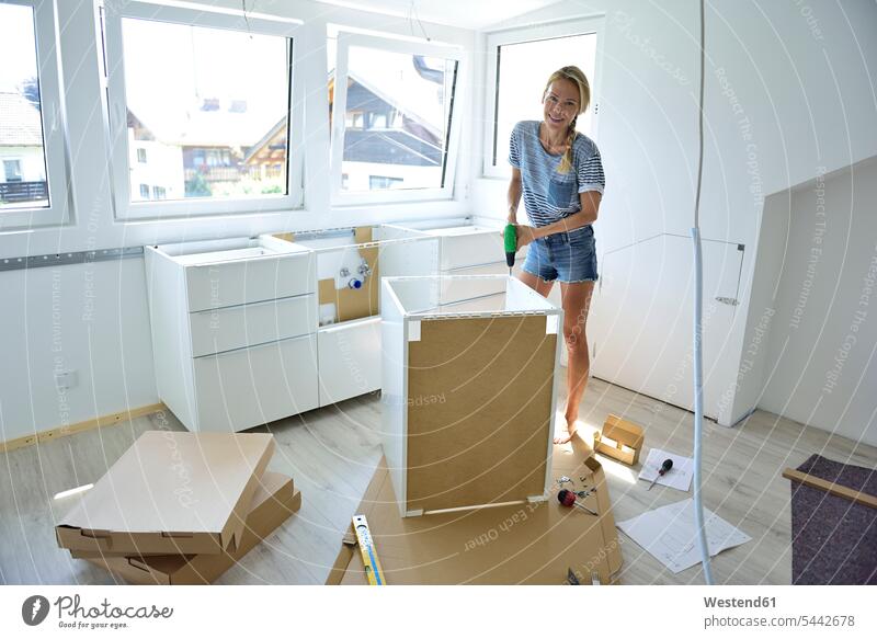 Woman assembling cabinet at home setting up building up build up set up woman females women DIY Doityourself Do it yourself Do-it-yourself Adults grown-ups