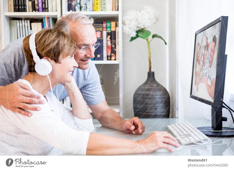 Senior couple at desk having a video conference with their family smiling smile twosomes partnership couples people persons human being humans human beings
