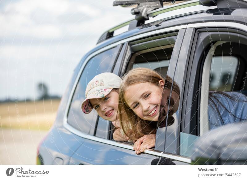 Girls sitting in car, looking out of window sister sisters girl females girls vacation Holidays happiness happy automobile Auto cars motorcars Automobiles