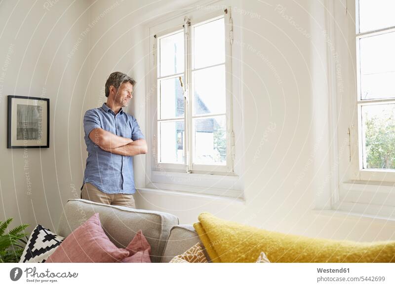Mature man at home eaning at window leaning arms crossed Arms Folded Folded Arms Crossed Arms Crossing Arms Arms Clasped men males confidence confident Adults