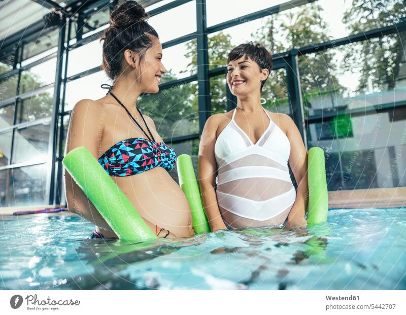 Two pregnant women doing water gymnastics in indoor swimming pool Pregnant Woman swimming bath indoor swimming pools aqua aerobics woman females