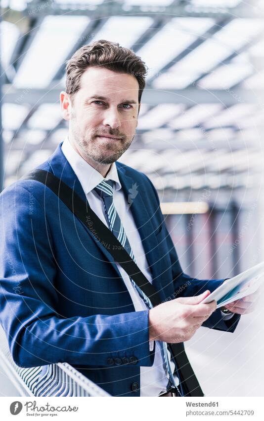Businessman standing on parking level holding digital tablet document paper documents papers reading Business man Businessmen Business men working At Work