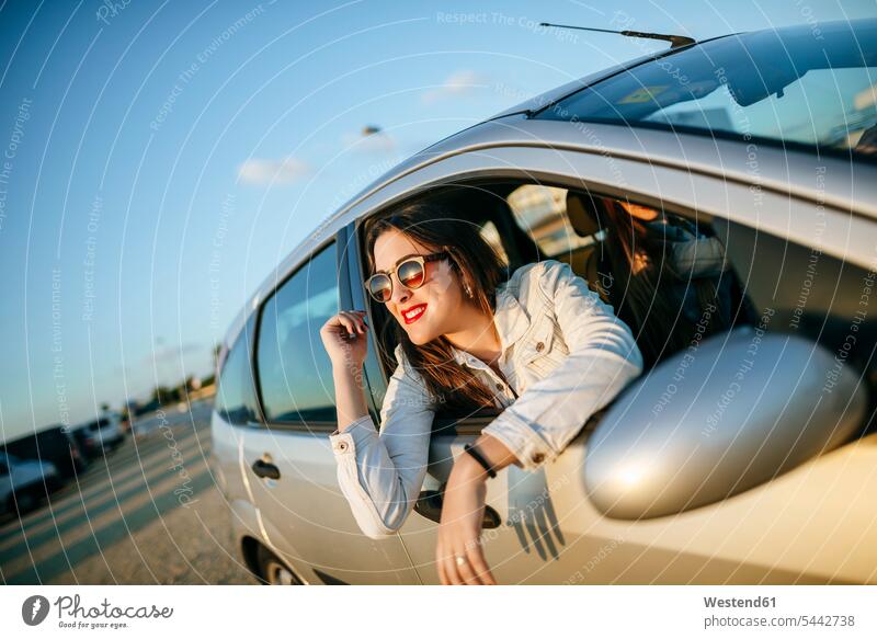 Young woman leaning out of car window automobile Auto cars motorcars Automobiles females women motor vehicle road vehicle road vehicles motor vehicles Adults