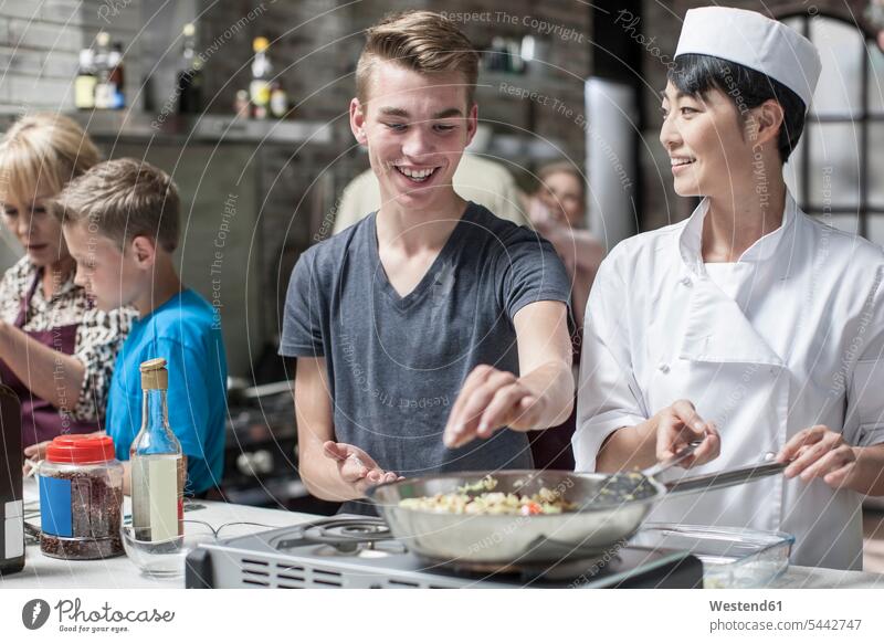 Teenager and female chef cooking together kitchen frying roasting female cook smiling smile cooking class cooks Chefs adding preparation prepare preparing