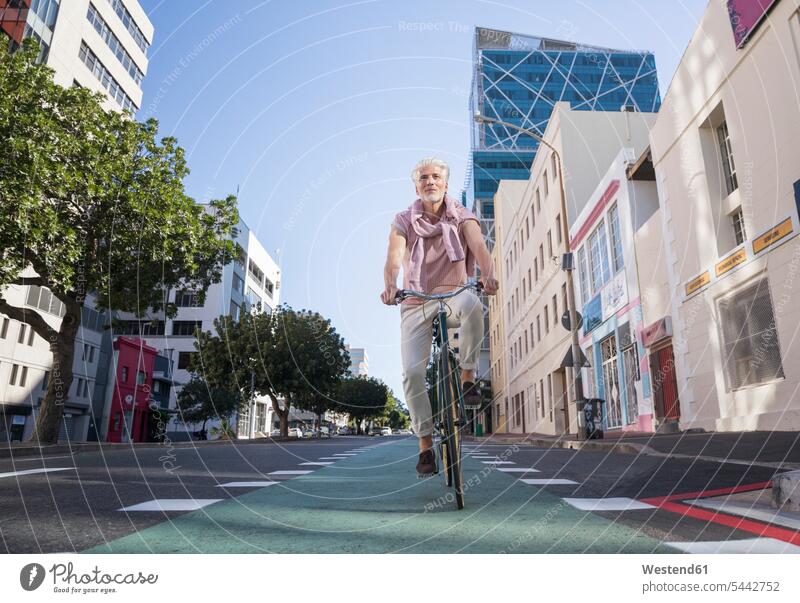 Mature man riding bicycle in the city town cities towns men males bikes bicycles riding bike bike riding cycling bicycling pedaling on the move on the way