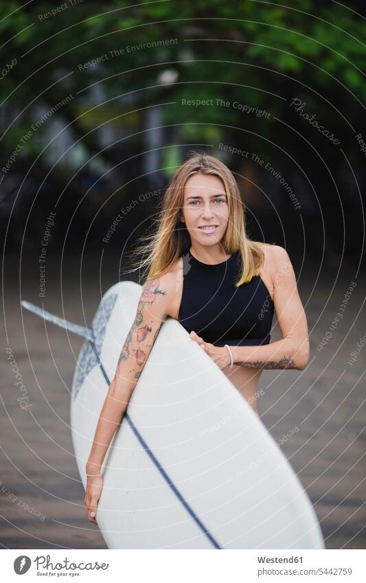 Portrait of smiling woman carrying surfboard on the beach females women surfing surf ride surf riding Surfboarding smile surfboards Adults grown-ups grownups