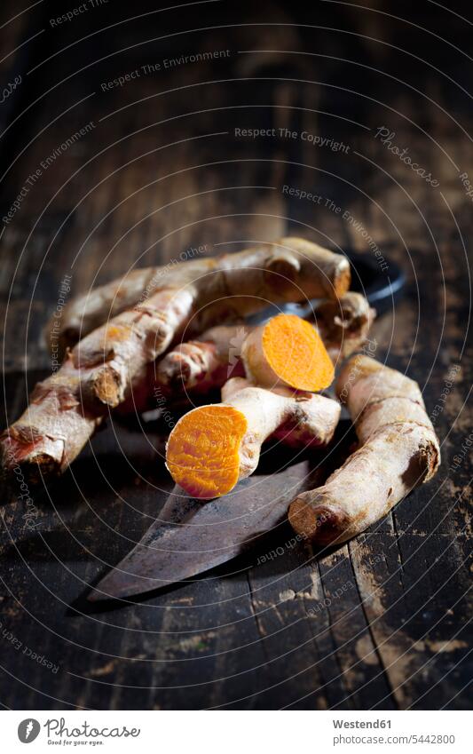 Whole and sliced turmeric and an old knife on dark wood uncooked still life still-lifes still lifes Freshness fresh healthy eating nutrition vitamines