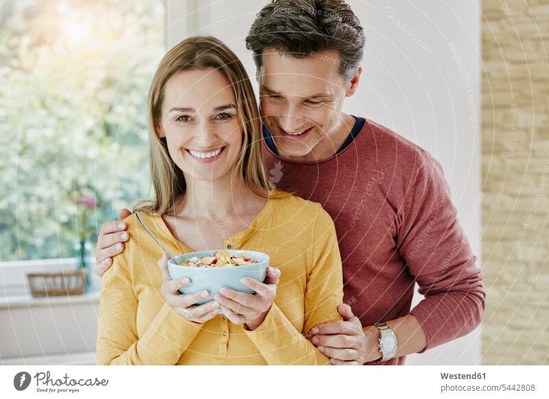Happy couple holding bowl with muesli at home happiness happy portrait portraits Granola Muesli cereals eating twosomes partnership couples smiling smile Food