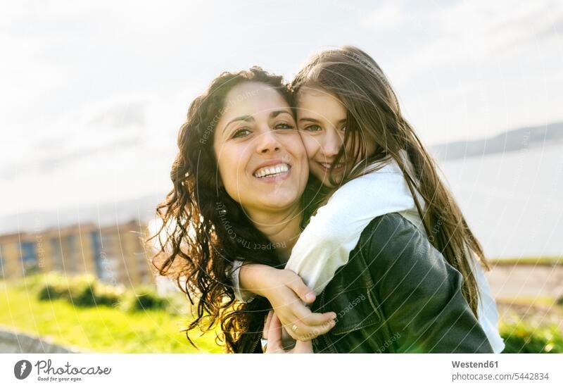Portrait of happy mother carrying daughter outdoors mommy mothers ma mummy mama happiness daughters relaxed relaxation parents family families people persons