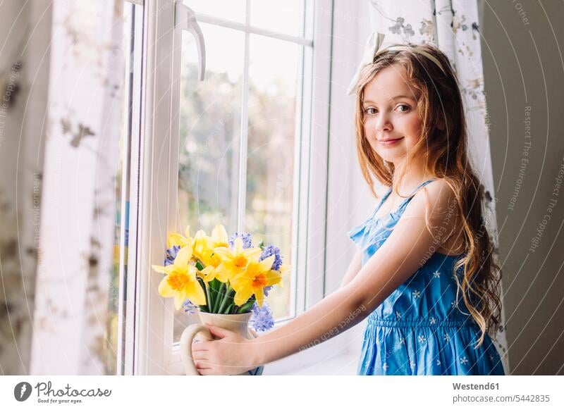 Portrait of smiling girl with flower vase of daffodils and hyacinths at home females girls portrait portraits child children kid kids people persons human being