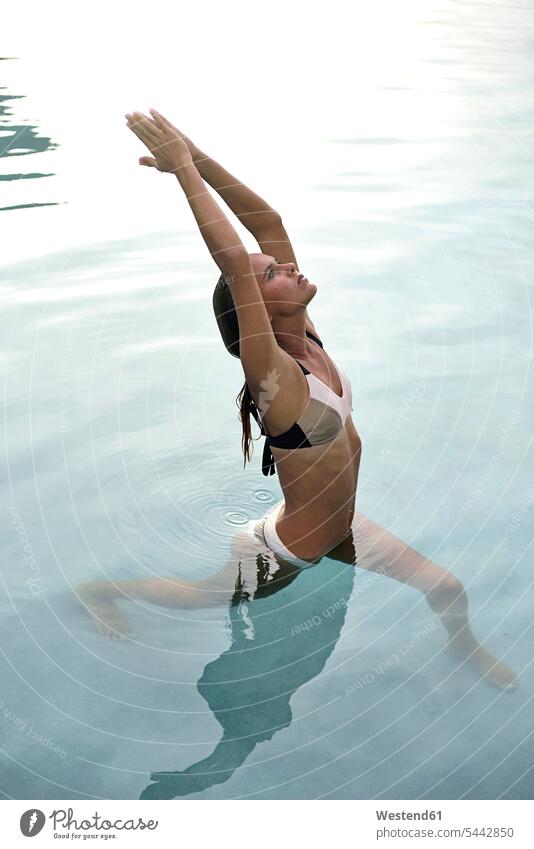 Young woman stretching in swimming pool exercise exercises females women pools swimming pools Adults grown-ups grownups adult people persons human being humans