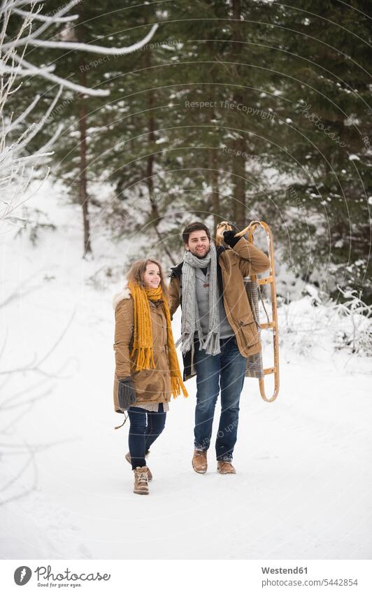 Happy young couple with sledge in winter forest sledges snow twosomes partnership couples weather people persons human being humans human beings happiness happy