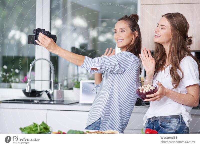 Food bloggers greeting their viewers in kitchen Selfies smile cameras wave human human being human beings humans person persons adult grown-up grown-ups grownup